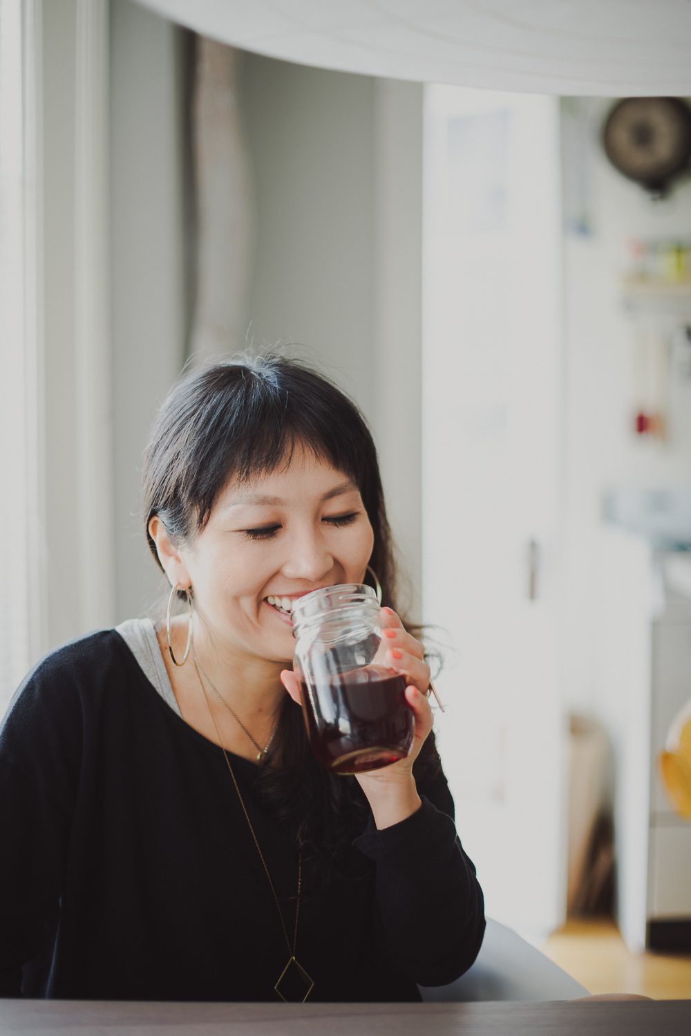 woman sipping tea out of mason jar