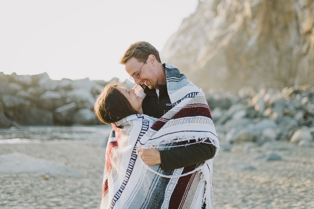 couple hugging in blanket at sunset on the beach