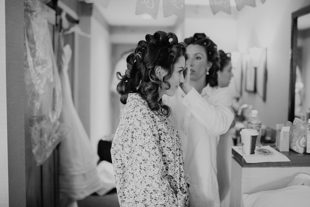bride getting her hair curled by a bridesmaid in black and white
