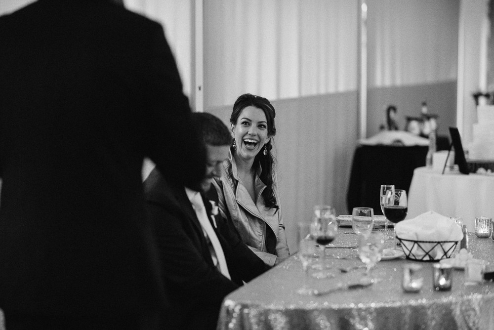 black and white of bride listening to a toast at her wedding reception