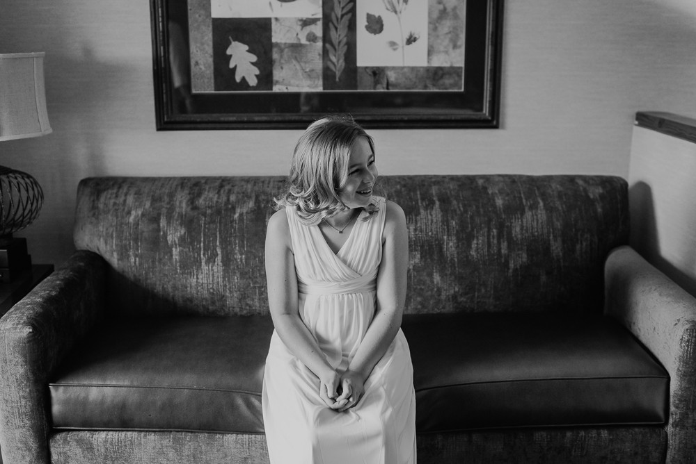 black and white of flower girl sitting on couch in hotel room
