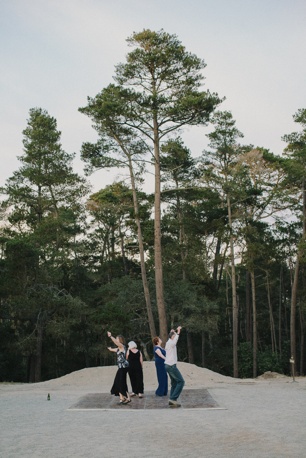 Guests dancing with tall trees behind them